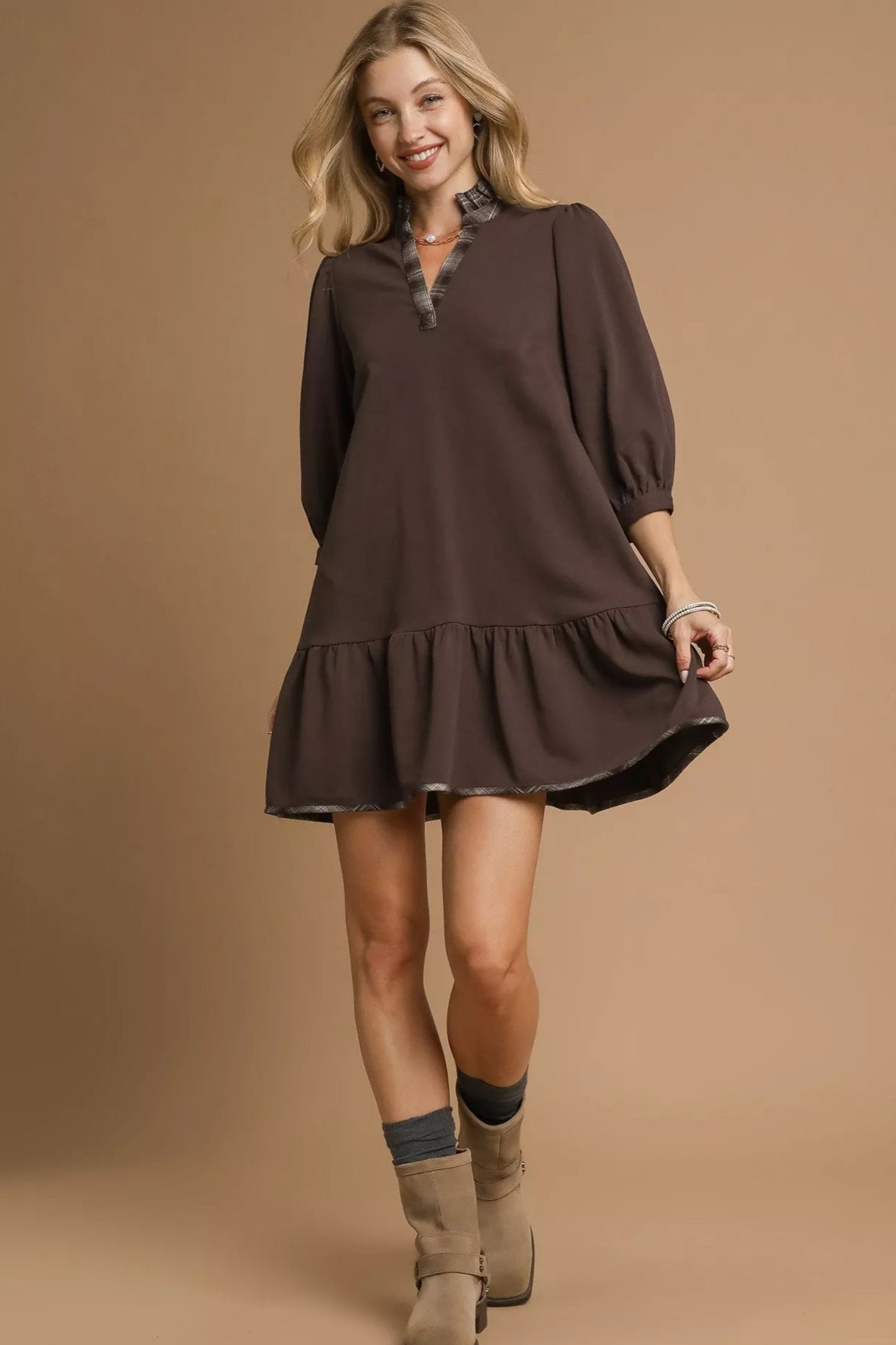 Woman wearing a brown dress with ruffled hem on a beige background