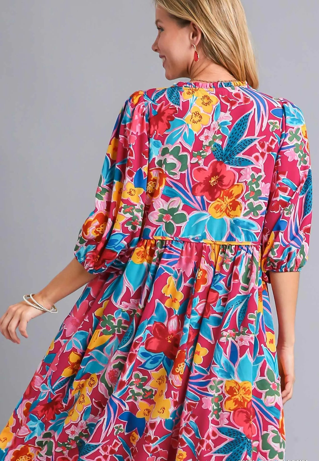 Woman wearing a colorful floral dress against a gray background