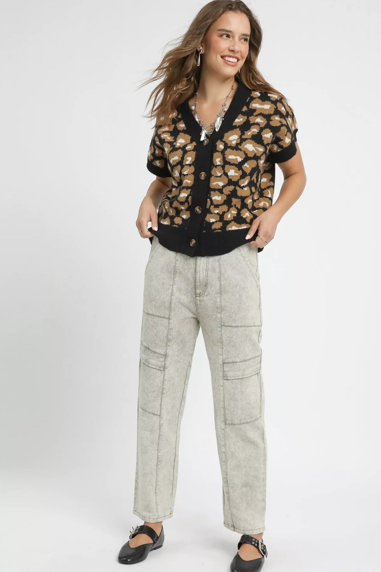 Woman wearing a patterned blouse and light pants on a white background