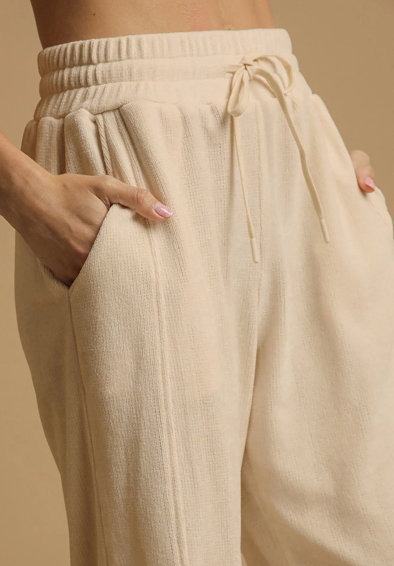 Beige pants with a drawstring waist on a beige background