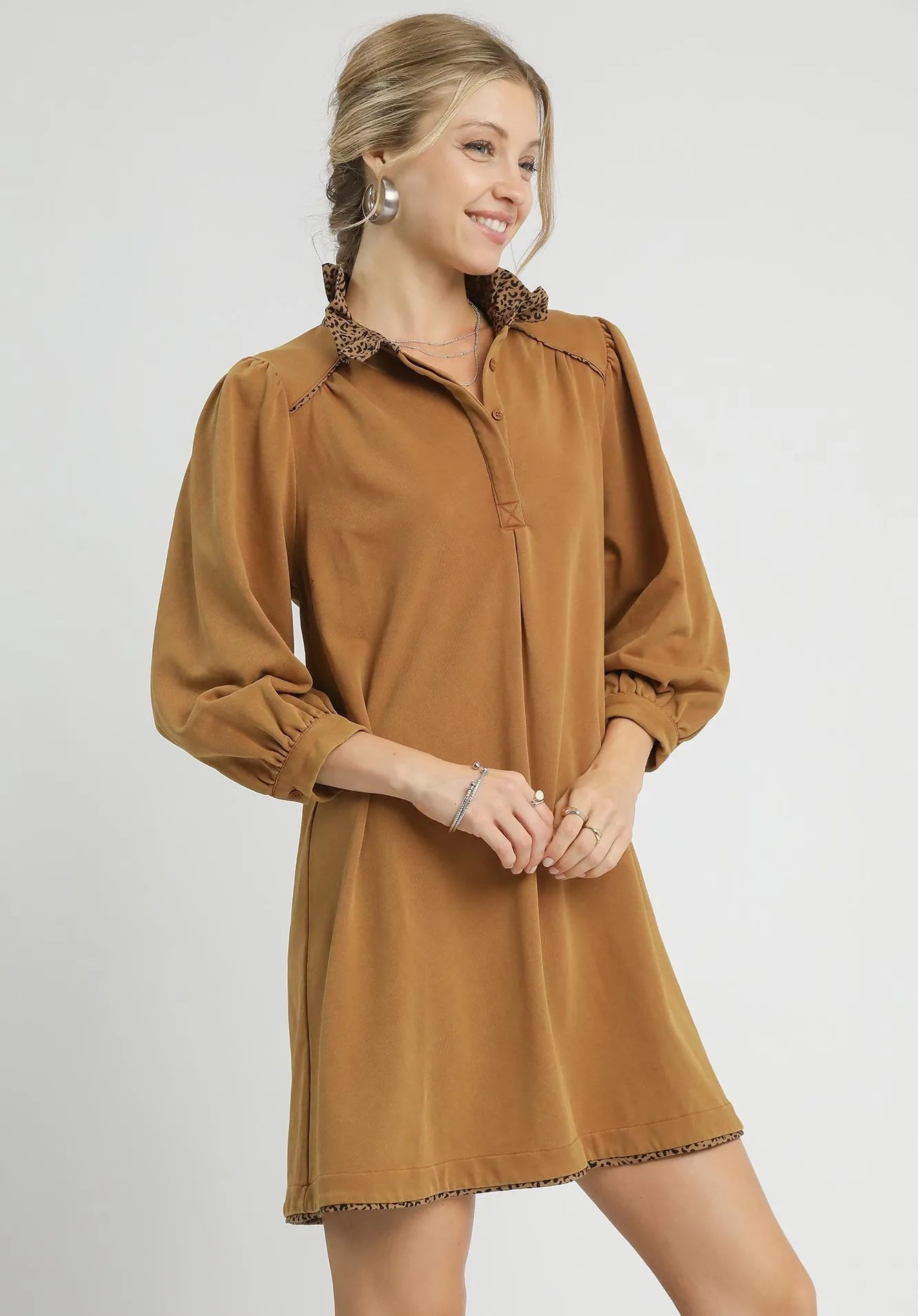 Woman wearing a brown dress with long sleeves on a white background