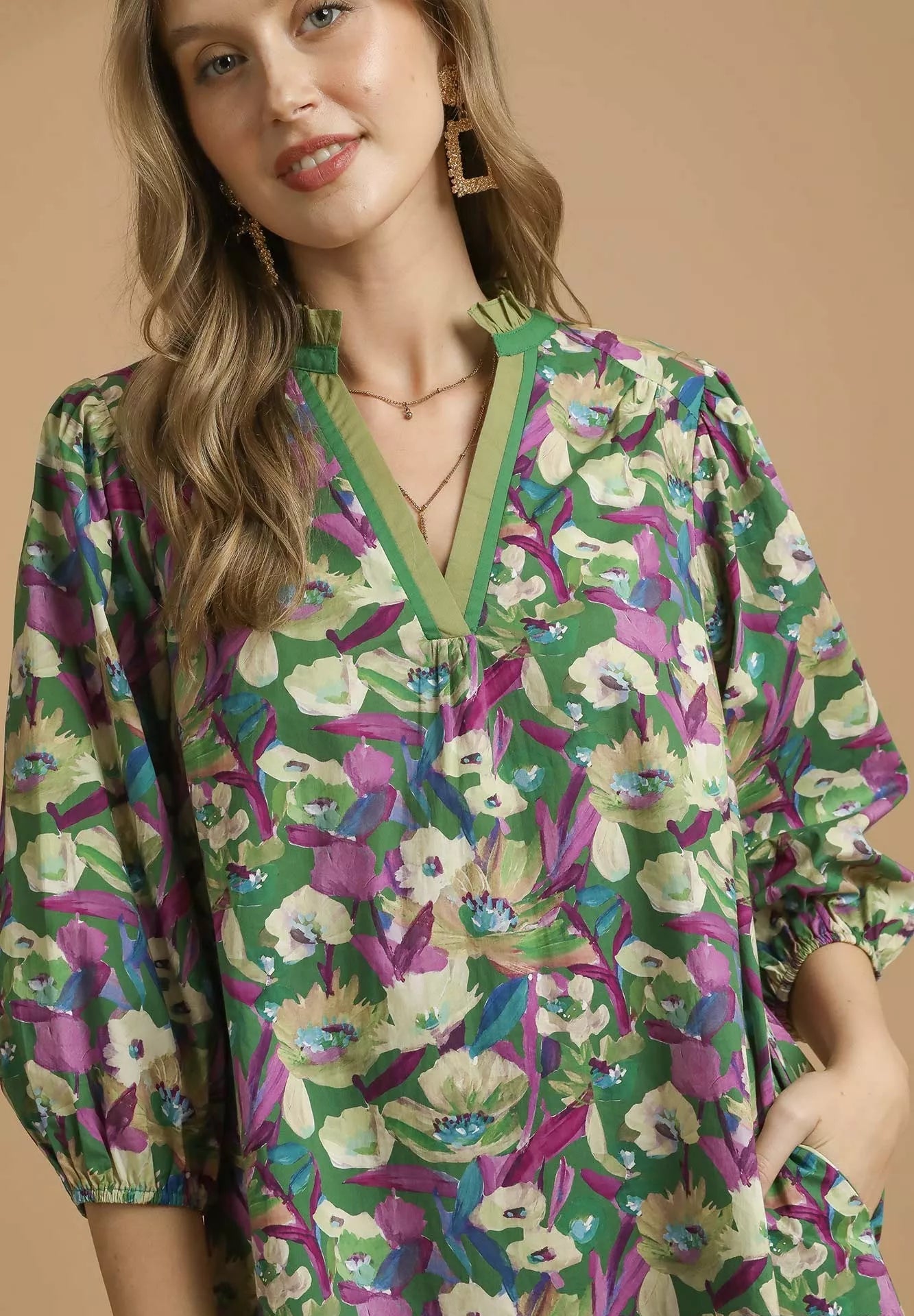 Woman wearing a green floral blouse against a beige background
