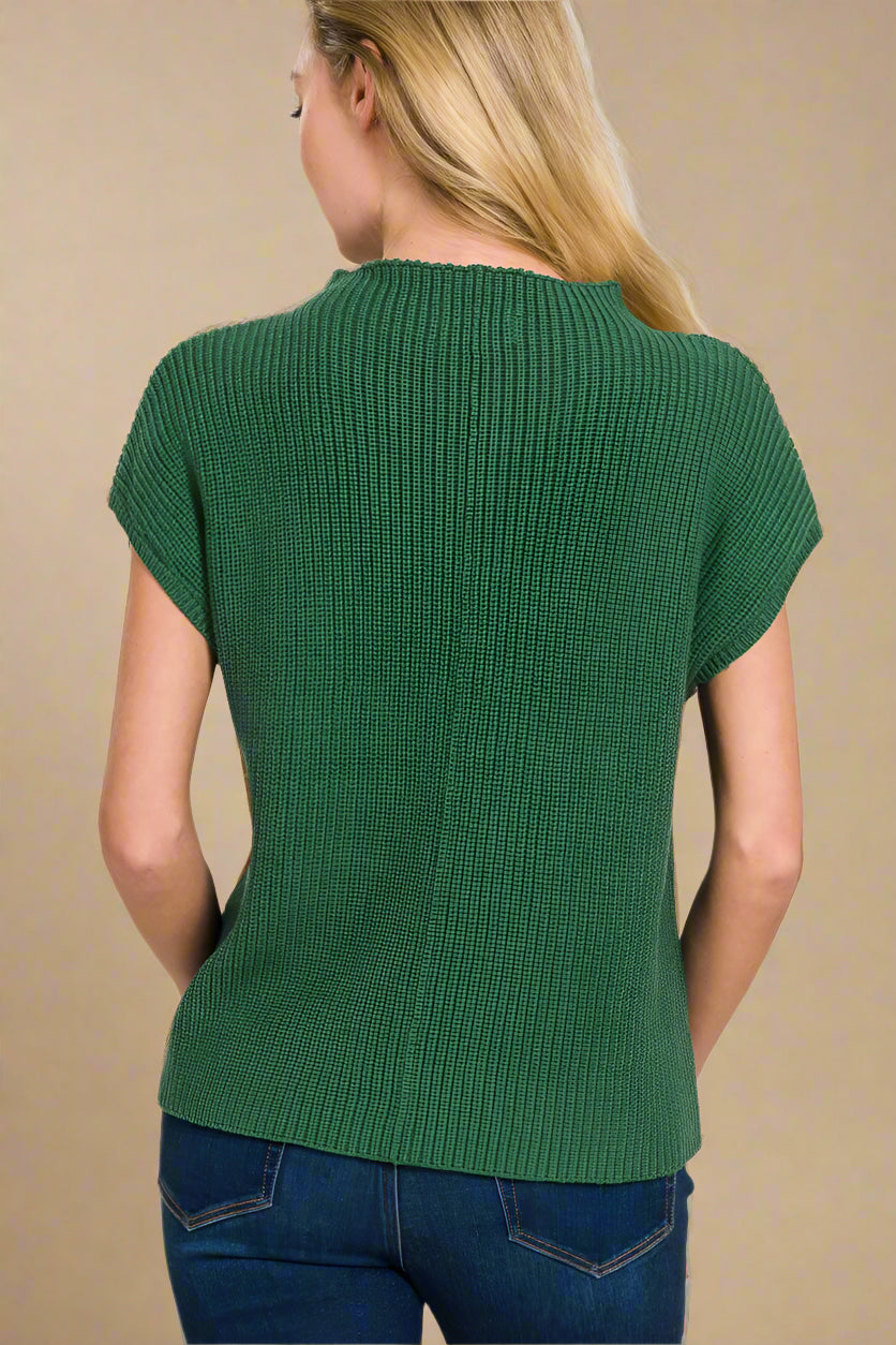 Green ribbed knit top worn by a person on a beige background