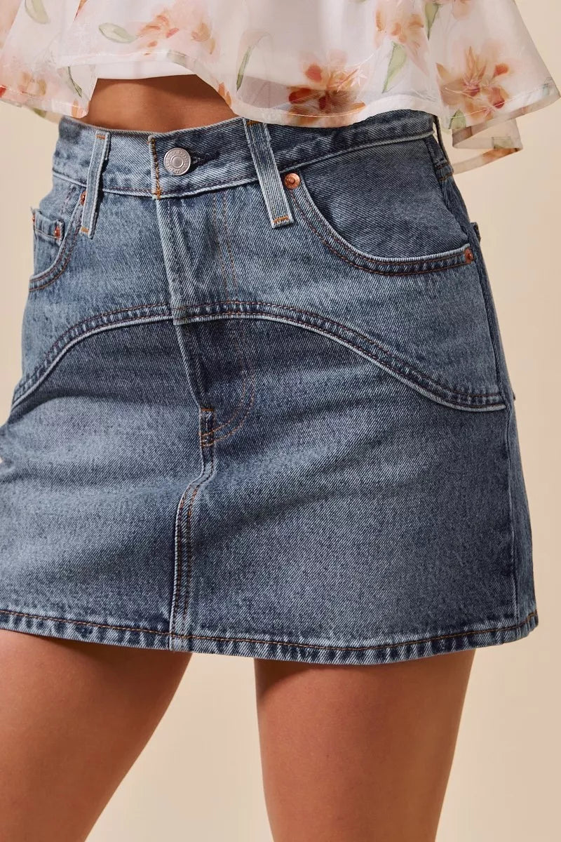 Denim skirt worn by a person with a neutral background