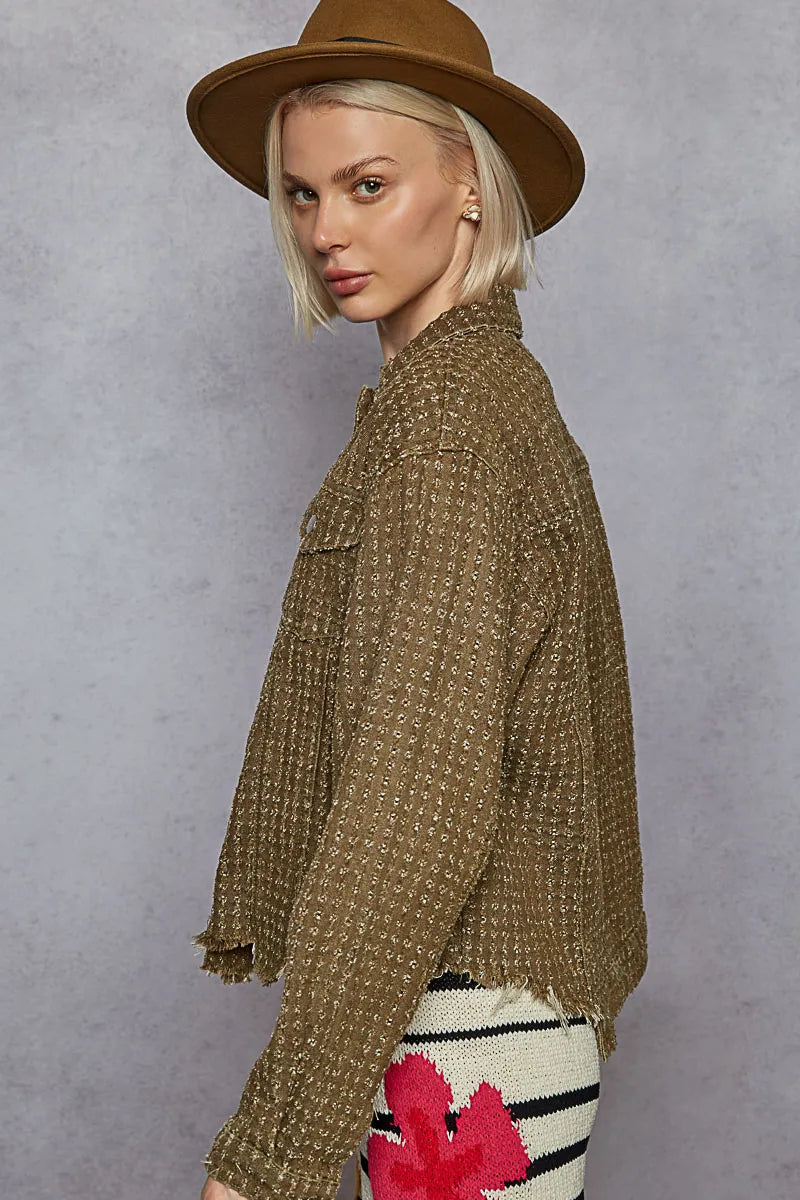 Woman wearing a brown patterned jacket and hat against a gray background