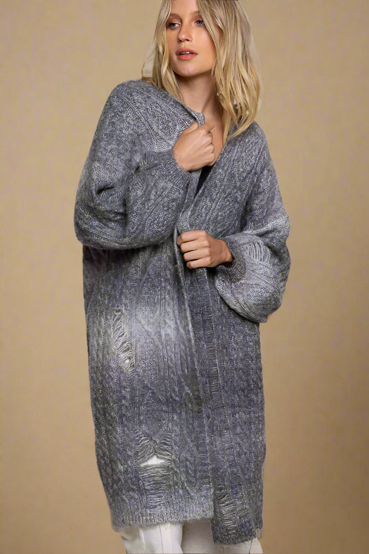 Woman wearing a long gray cardigan against a plain background