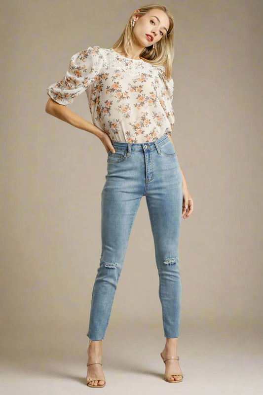 Woman wearing a floral blouse and blue jeans on a beige background
