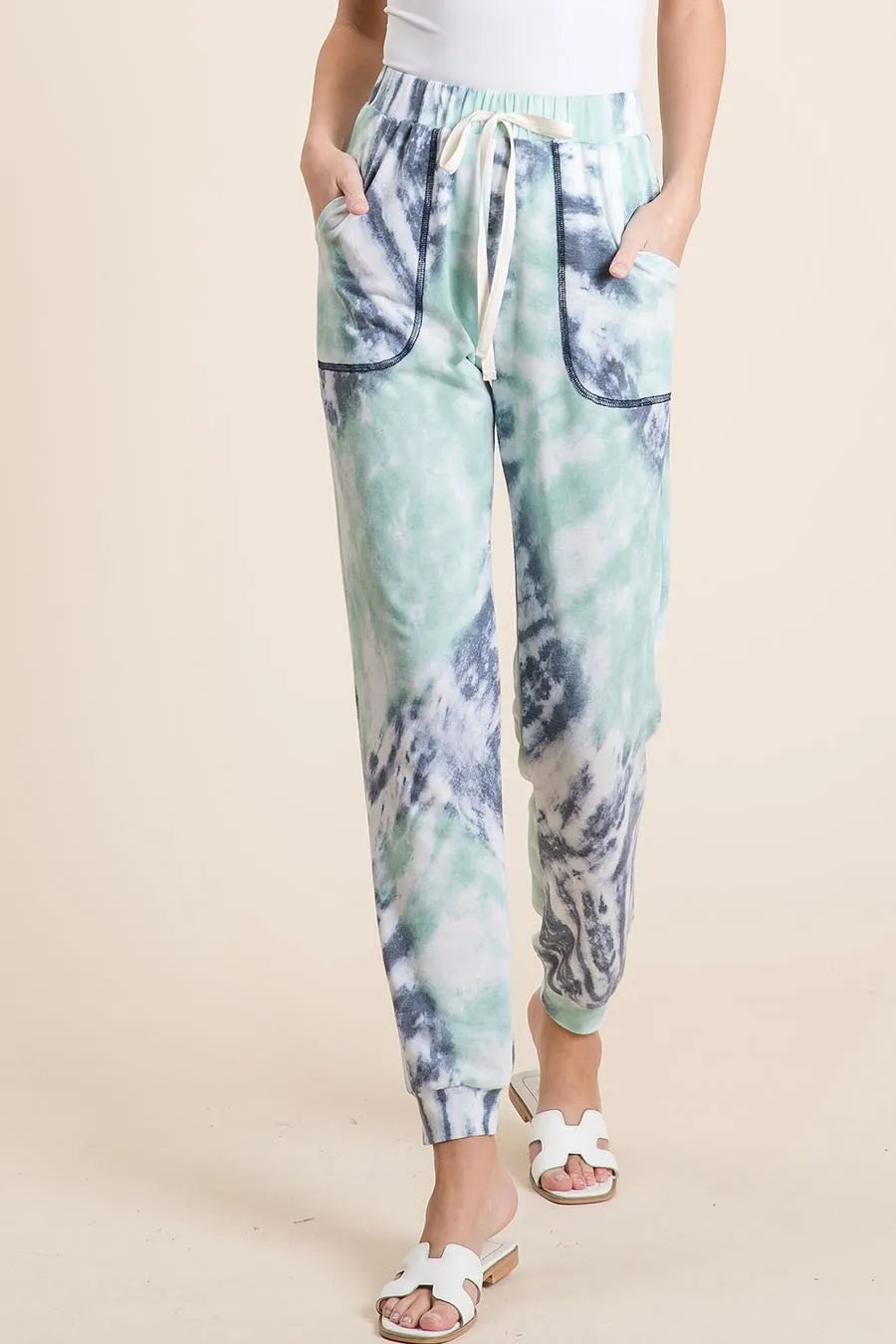 Tie-dye jogger pants worn by a person on a beige background