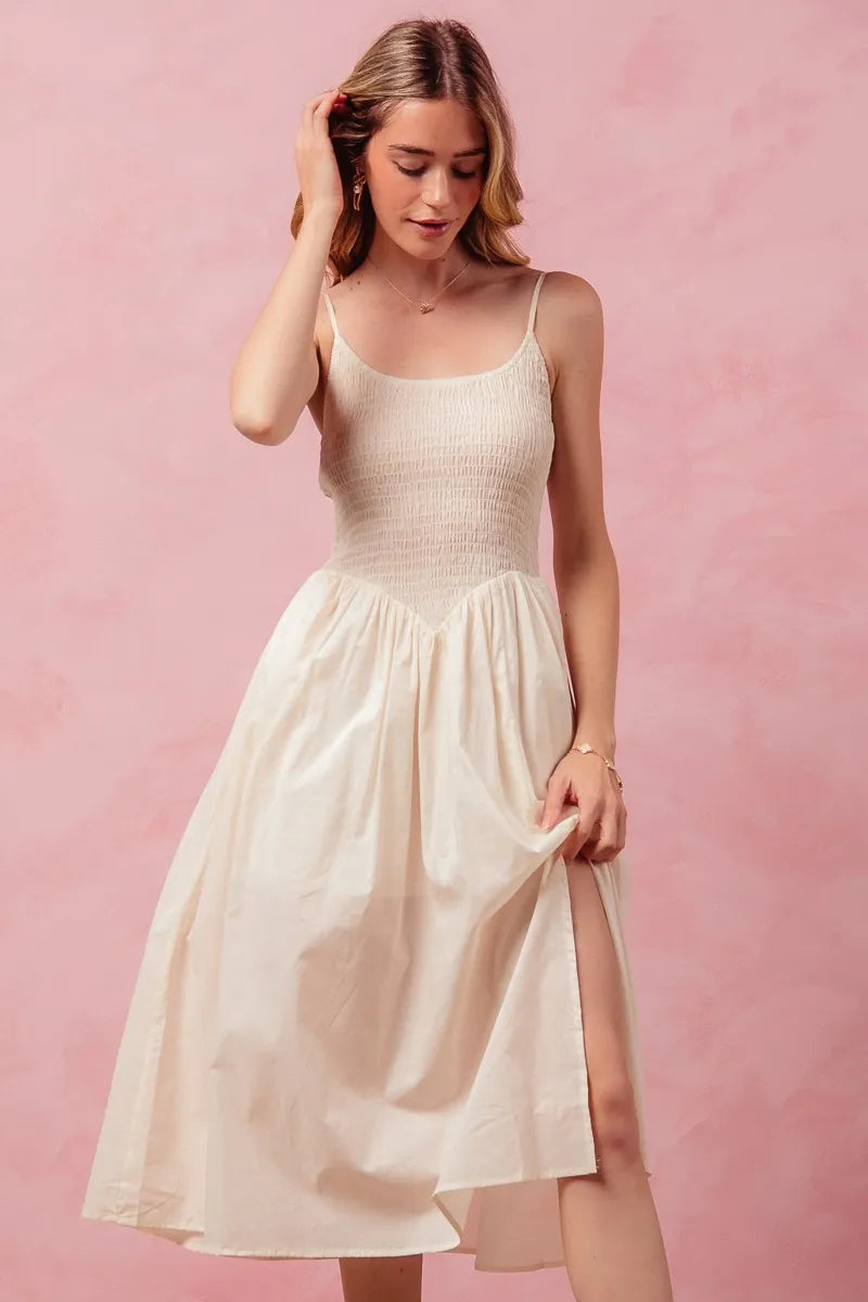 Woman wearing a beige dress against a pink background