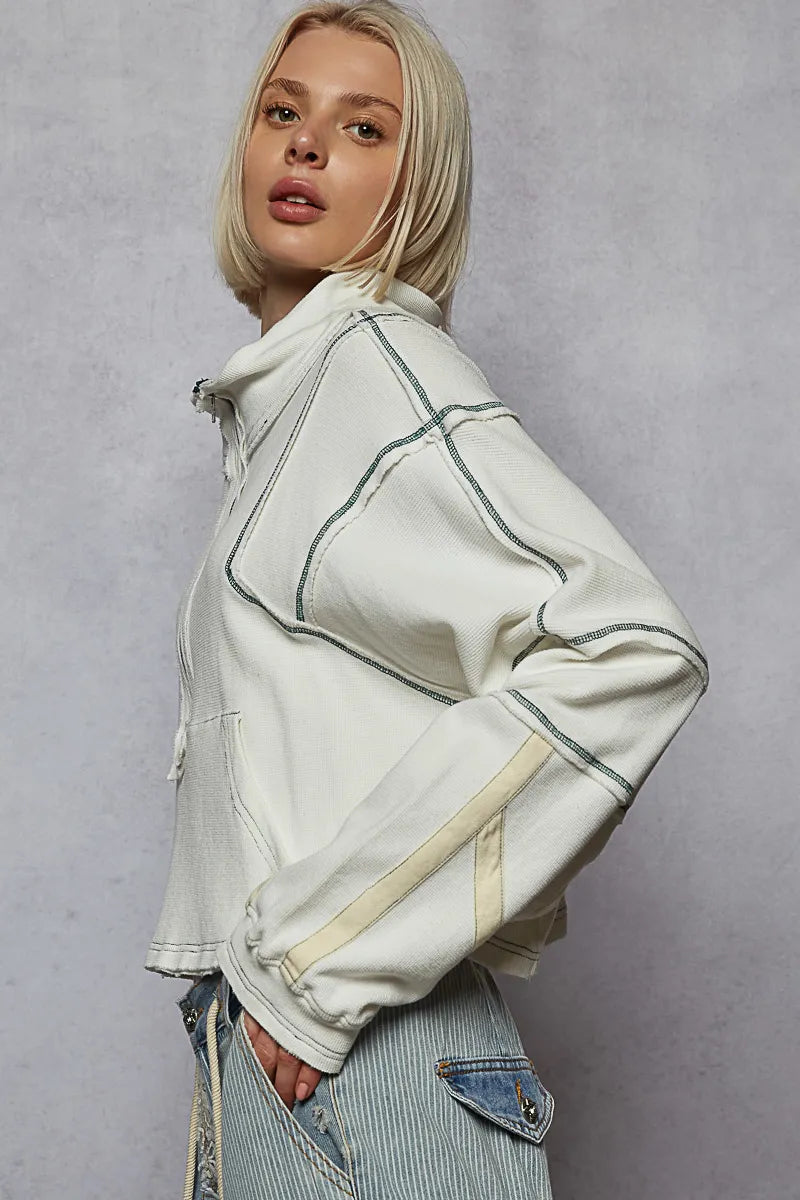 Person wearing a light-colored jacket with contrasting piping on a gray background