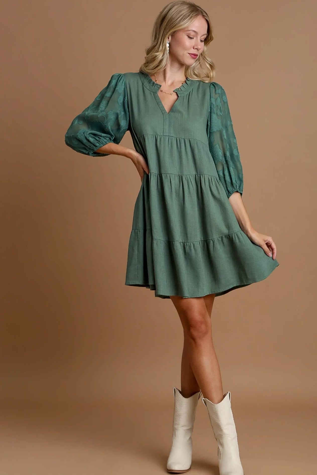 Woman wearing a green dress with white boots on a brown background