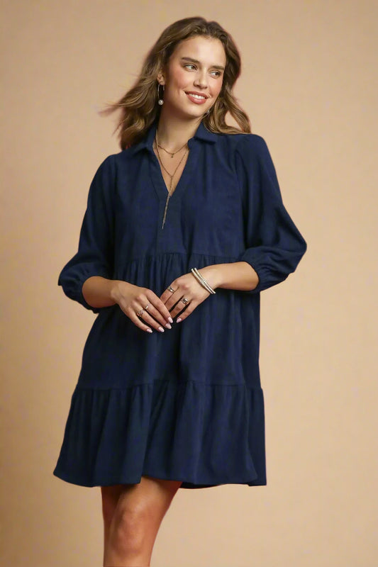 Woman wearing a navy dress against a beige background