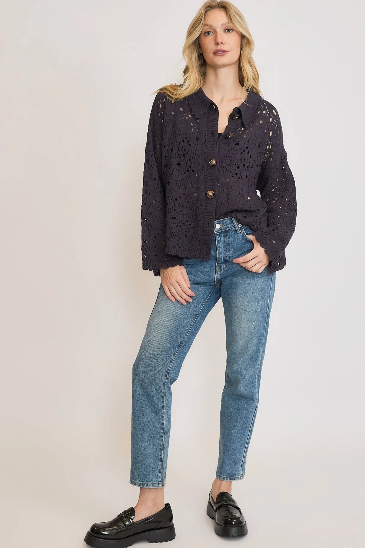 Woman wearing a dark navy button-up shirt and light blue jeans on a white background