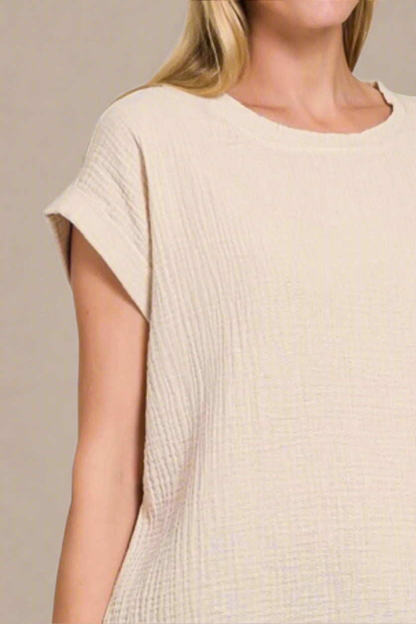 Beige short-sleeve top worn by a person on a beige background