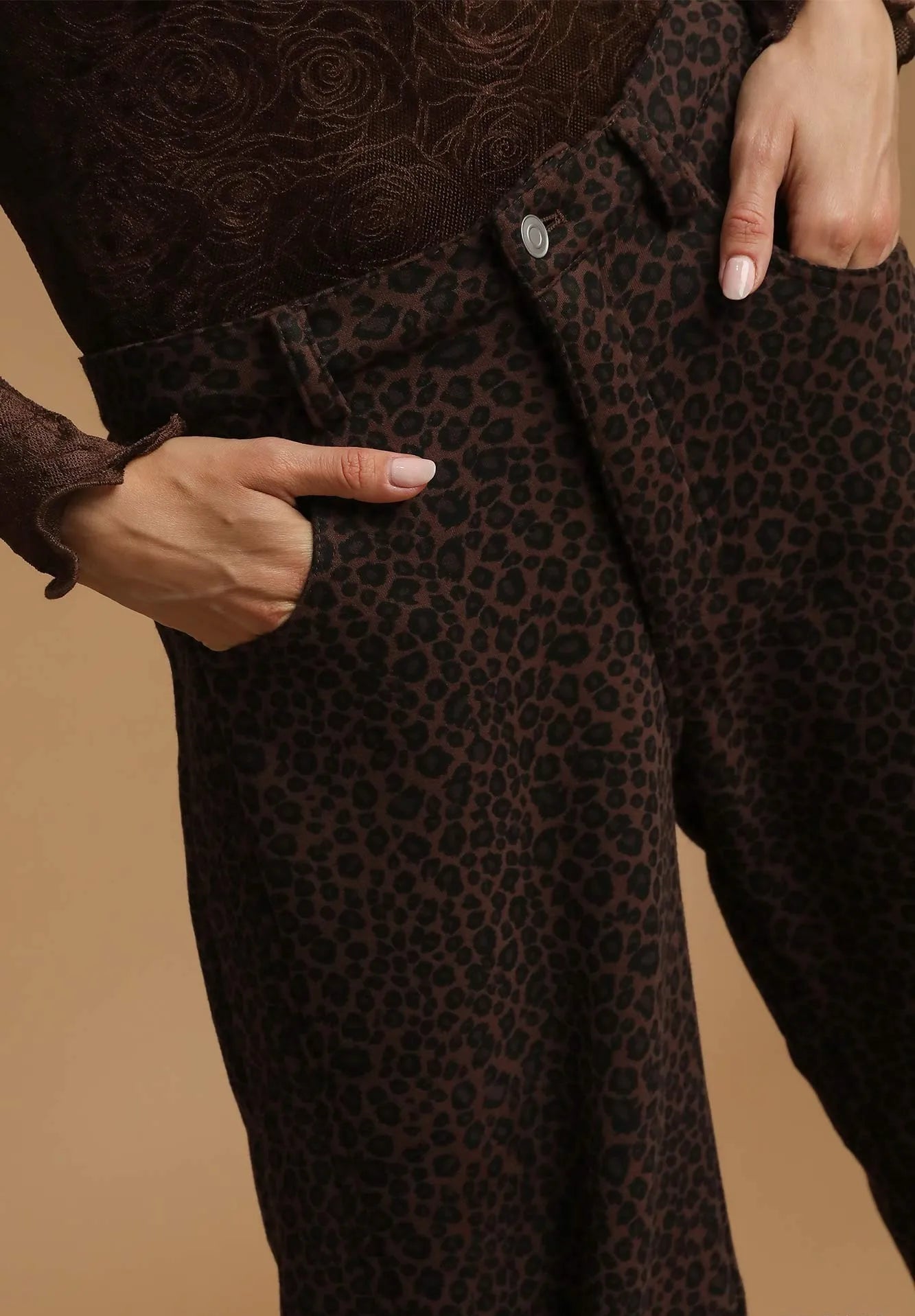 Brown leopard print coat with a hand pointing to it on a beige background