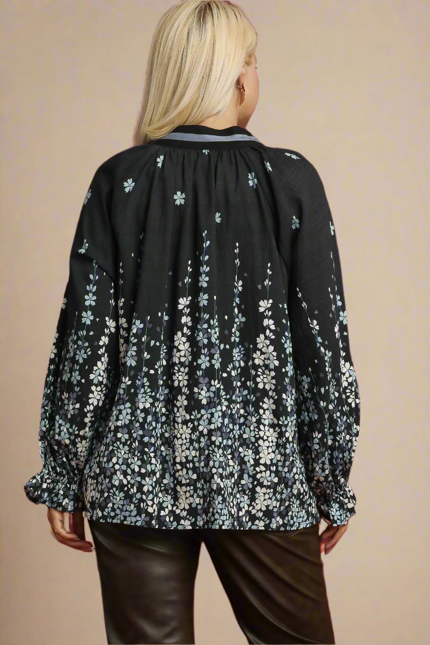 Woman wearing a black floral blouse against a beige background