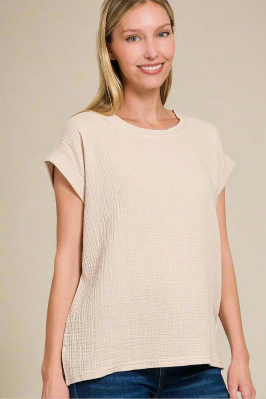 Woman wearing a beige sleeveless top on a beige background