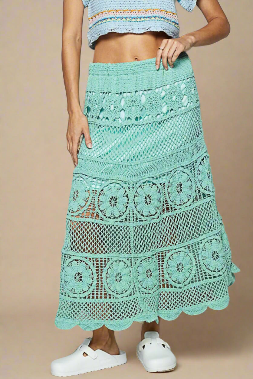 Person wearing a light blue crochet skirt on a plain background