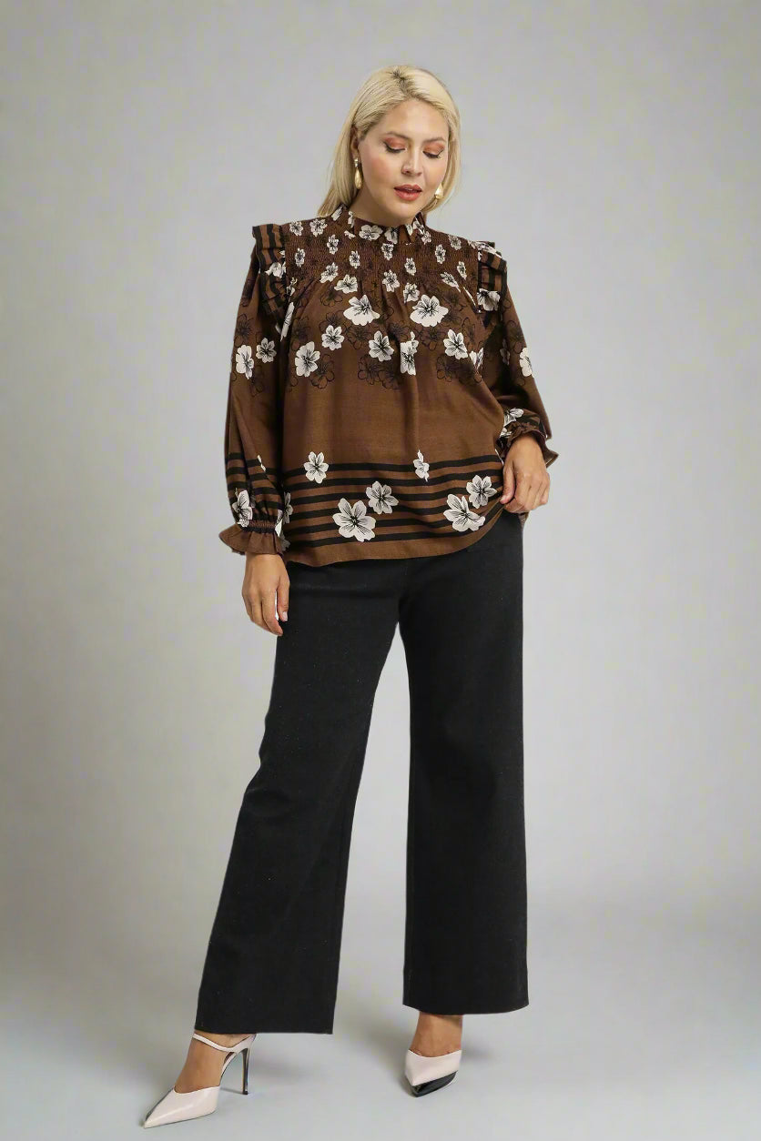 Woman wearing a brown floral blouse and black pants on a white background