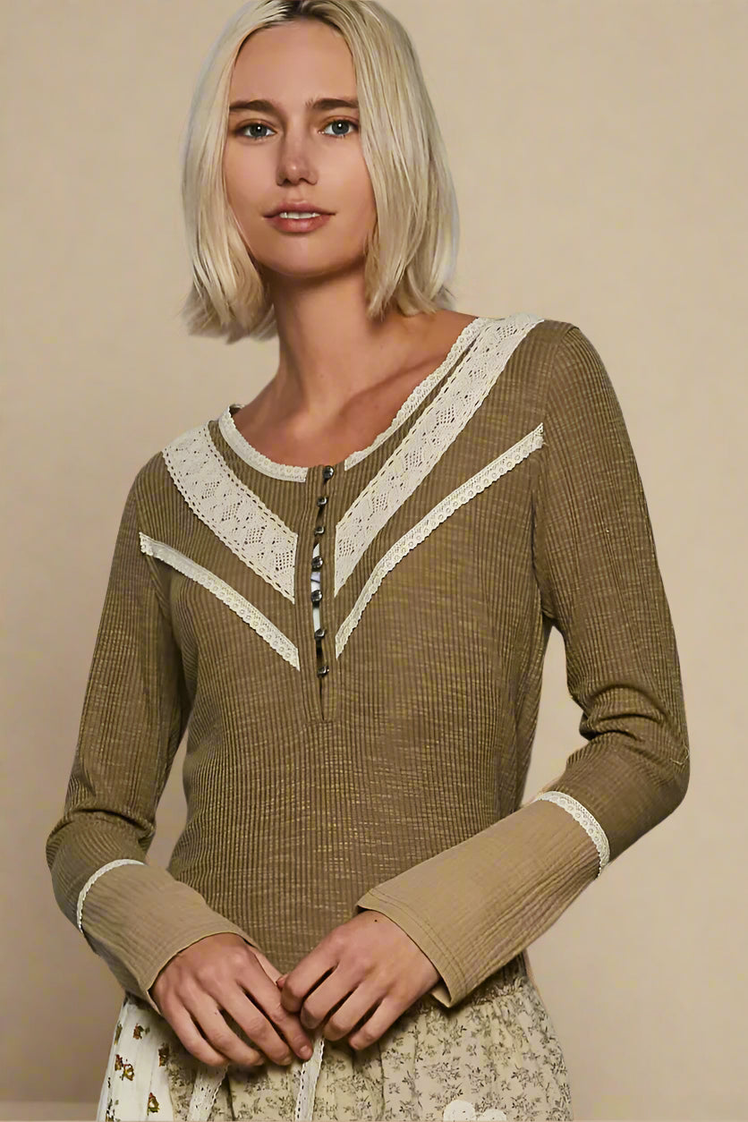 Woman wearing a brown long-sleeve top with lace details against a beige background