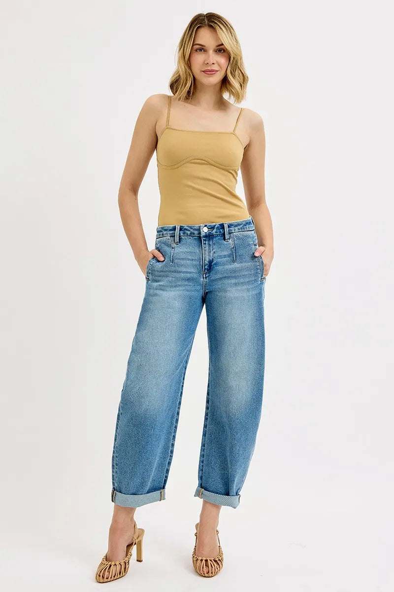Woman wearing a beige tank top and blue jeans on a white background