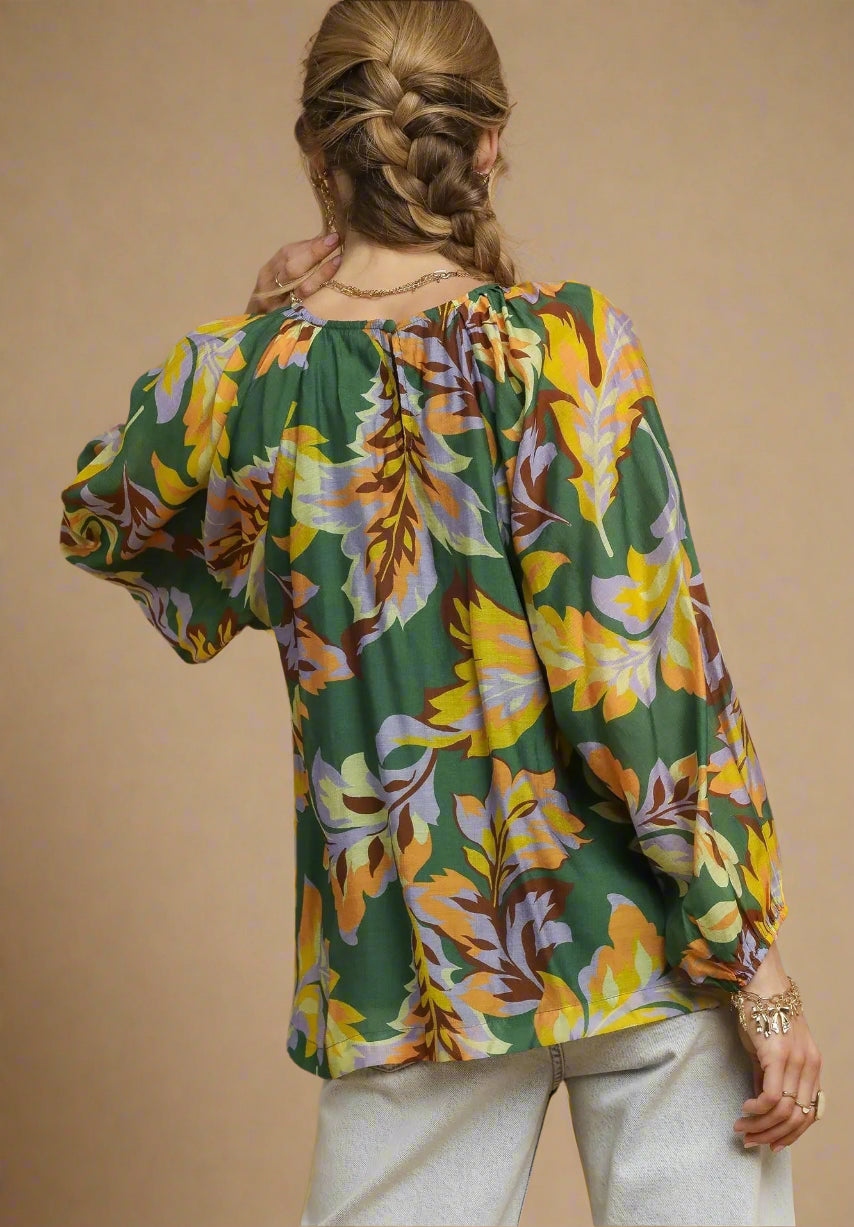 Woman wearing a colorful floral blouse with a green background