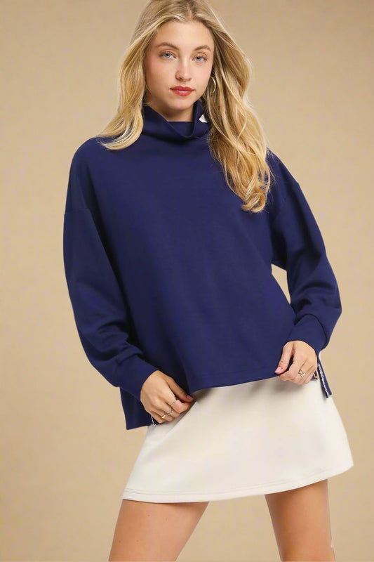 Woman wearing a blue sweater and white skirt on a white background