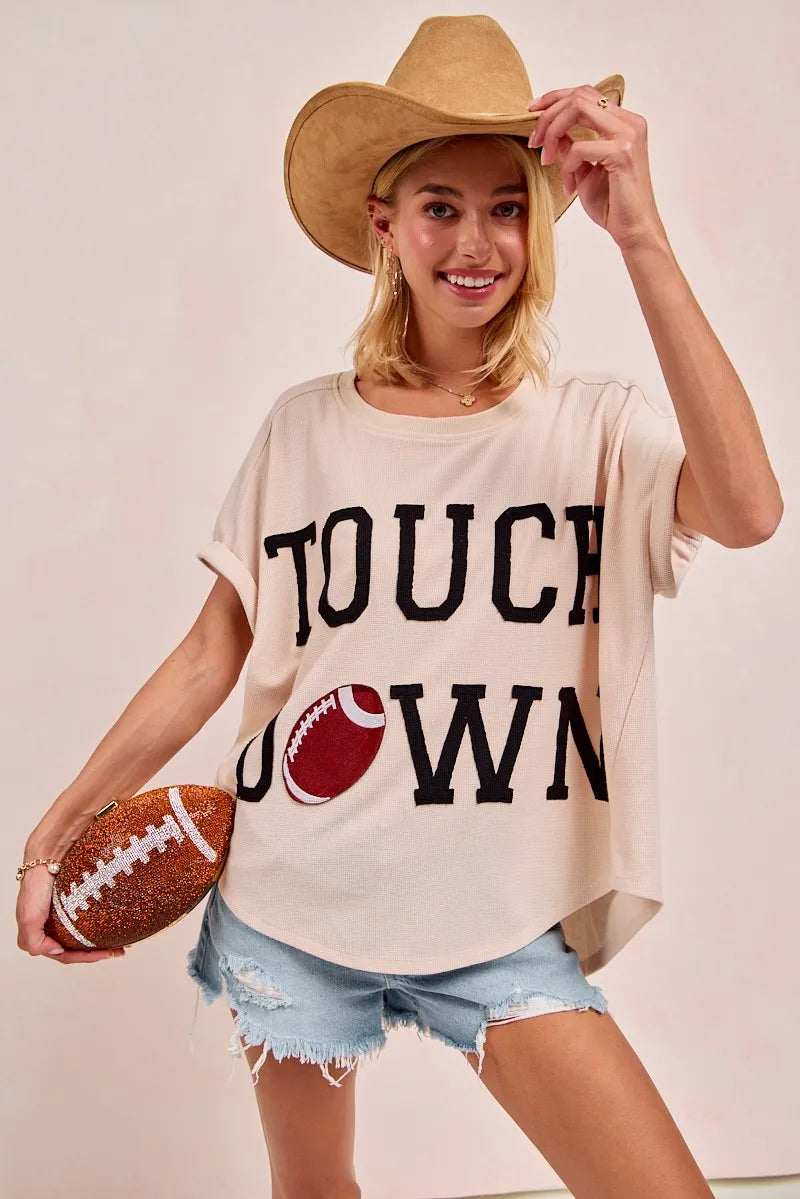 Woman wearing a 'Touchdown' t-shirt and cowboy hat, holding a football.