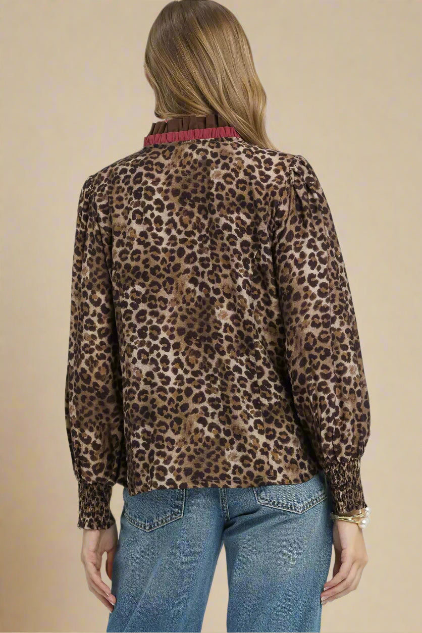 Person wearing a leopard print blouse with a plain background