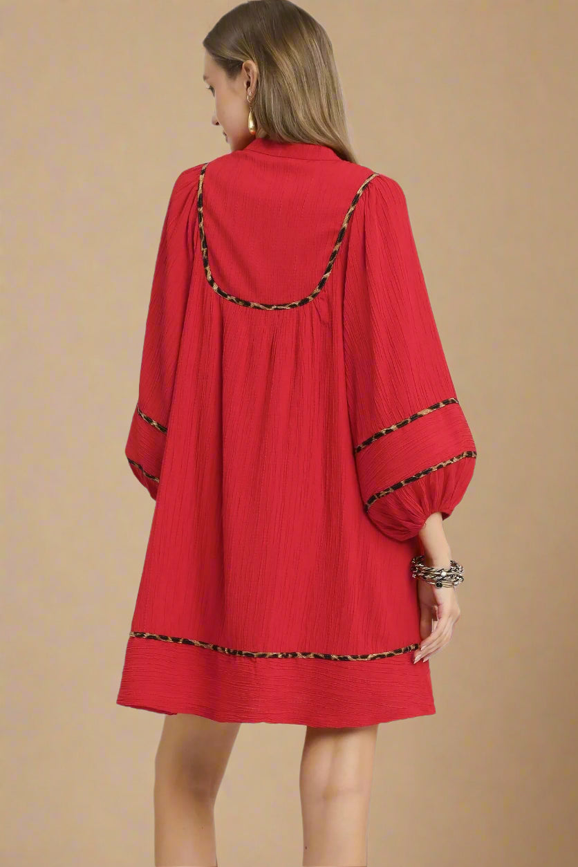 Red dress with black trim on a beige background