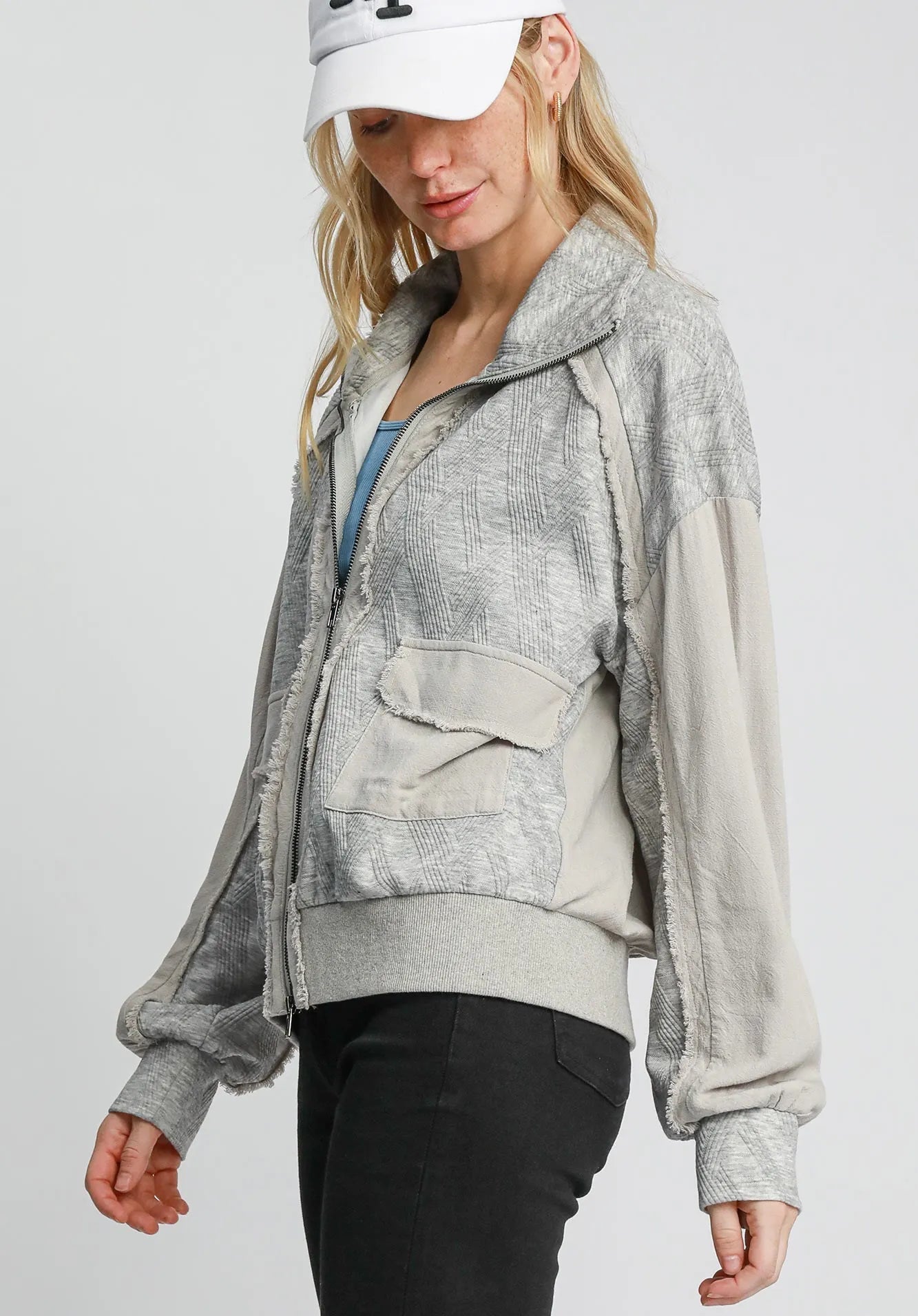 Woman wearing a gray jacket with a white cap on a light gray background