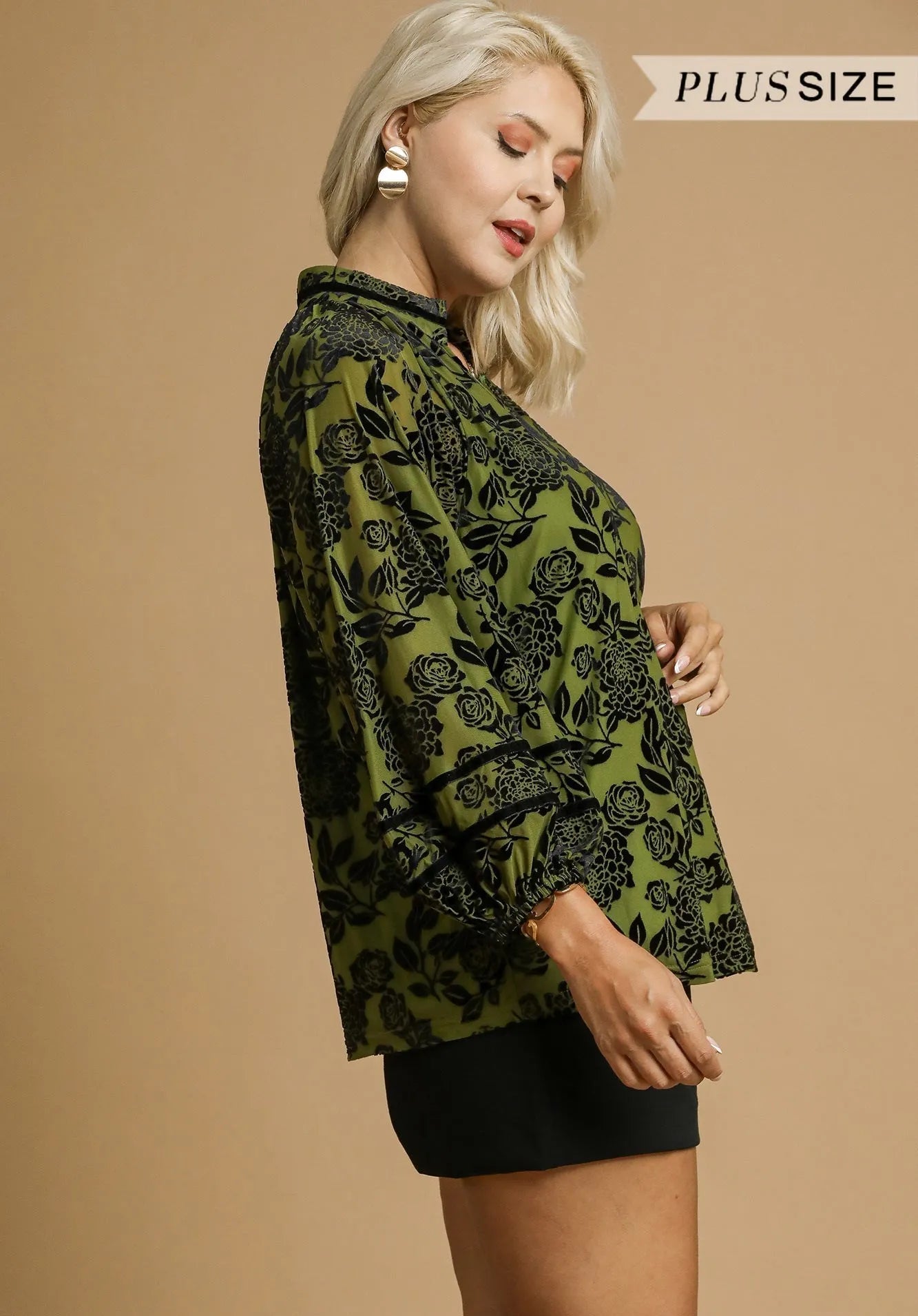 Woman wearing a green floral blouse against a beige background