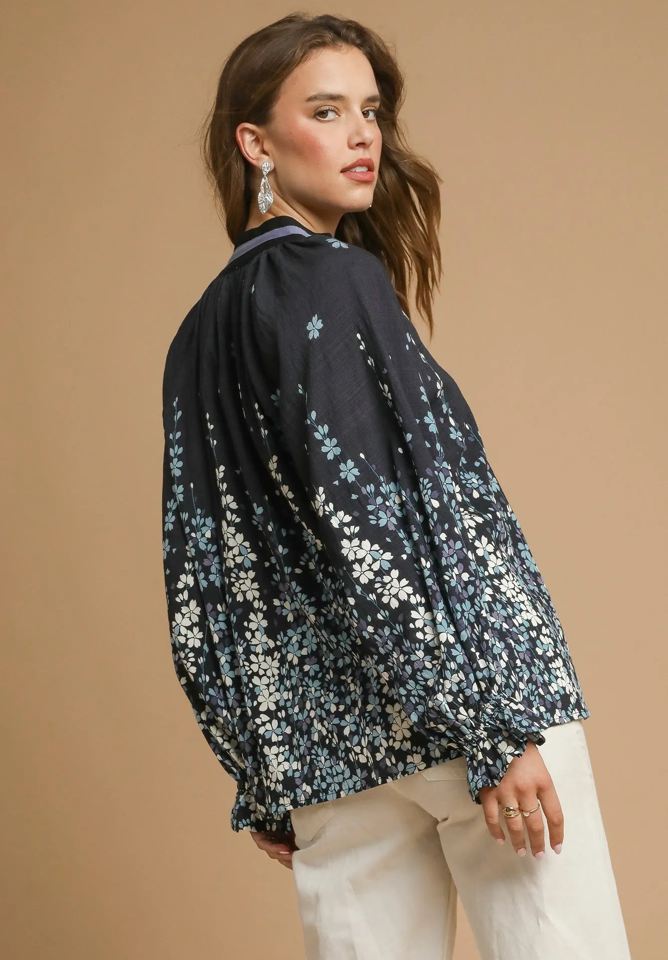 Woman wearing a black floral blouse against a beige background