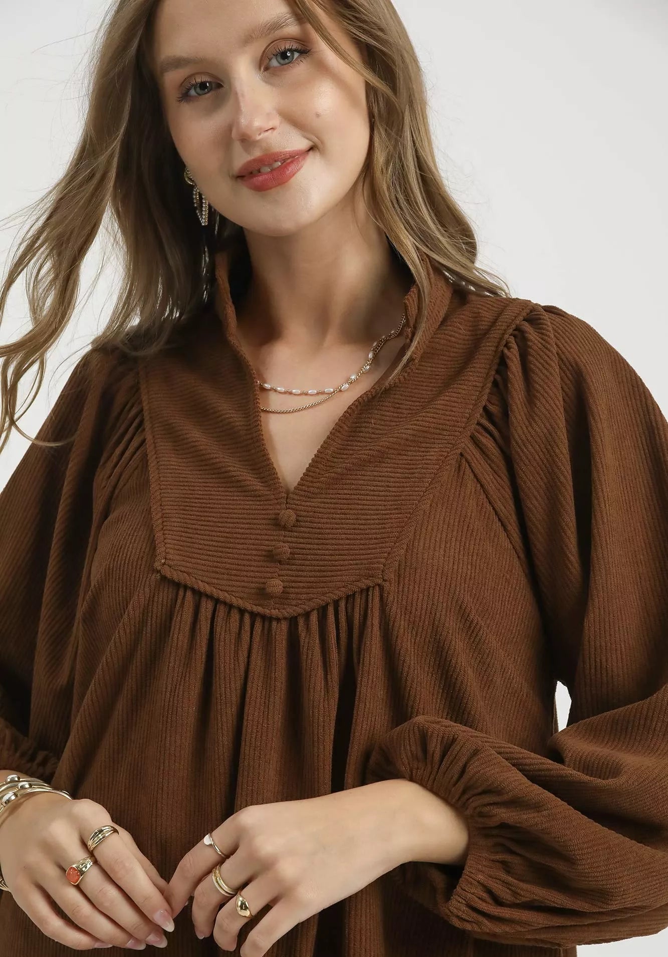 Woman wearing a brown blouse with a plain background