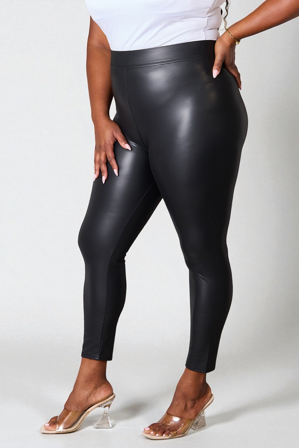 Person wearing black leather leggings on a white background