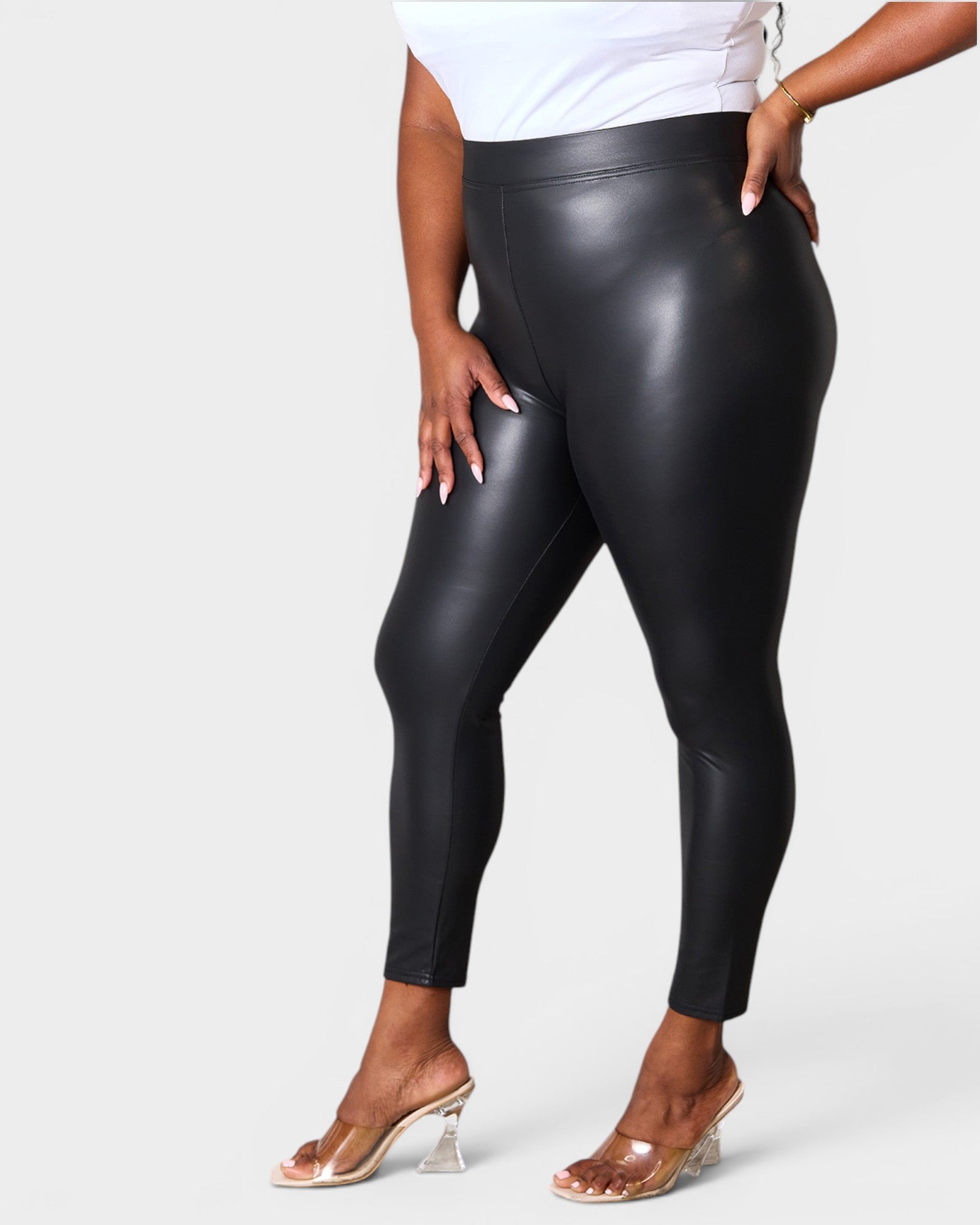 Person wearing black leather leggings on a white background
