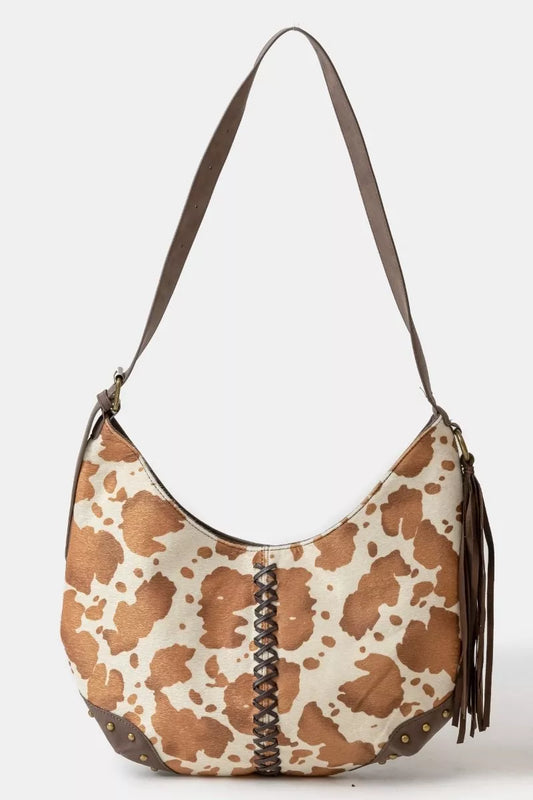 Brown and white patterned handbag with a brown strap on a light gray background