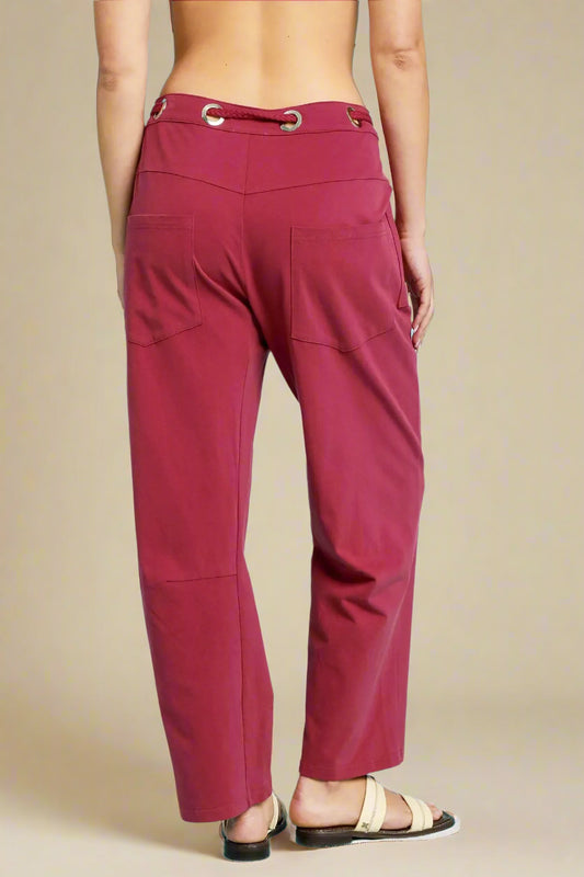 Wine-colored pants on a person against a beige background