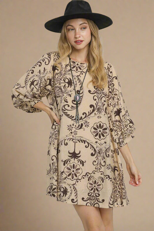 Woman wearing a patterned dress and black hat on a gray background