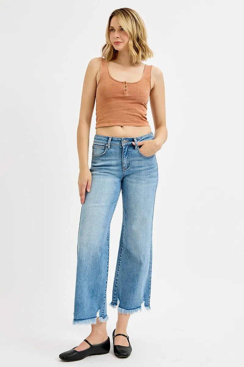 Woman wearing a brown tank top and blue jeans on a white background