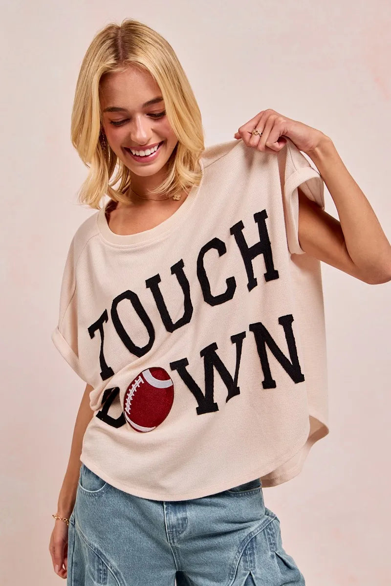 Woman holding a t-shirt with 'Touchdown' and a football graphic on a plain background