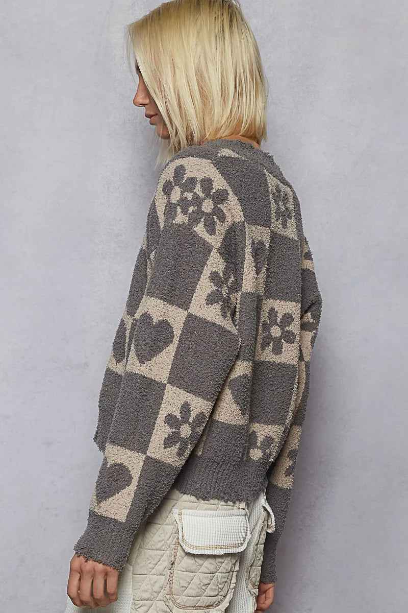 Person wearing a patterned sweater against a plain background