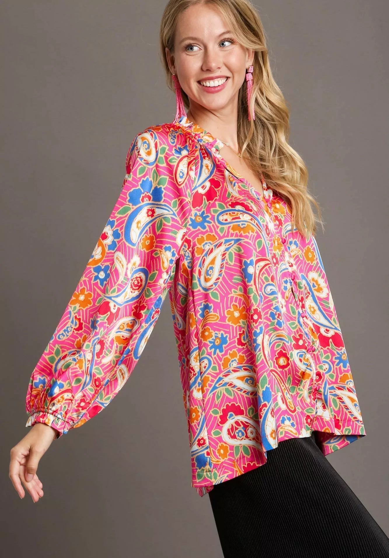 Woman wearing a colorful patterned blouse with long sleeves on a gray background