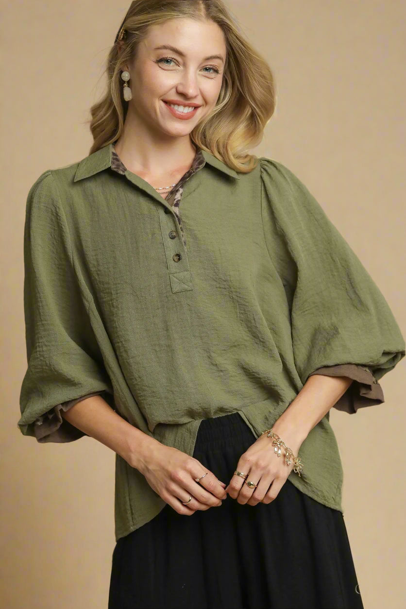 Woman wearing an olive green shirt with a plain background