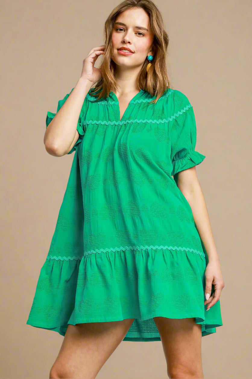 Woman wearing a green dress with lace details on a plain background