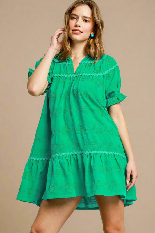 Woman wearing a green dress with lace details on a plain background