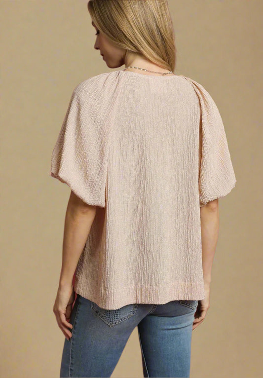 Woman wearing a beige blouse and blue jeans against a red background