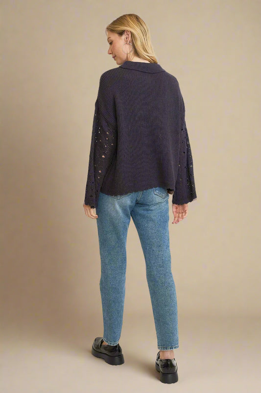 Woman wearing a dark blue jacket and light blue jeans on a beige background