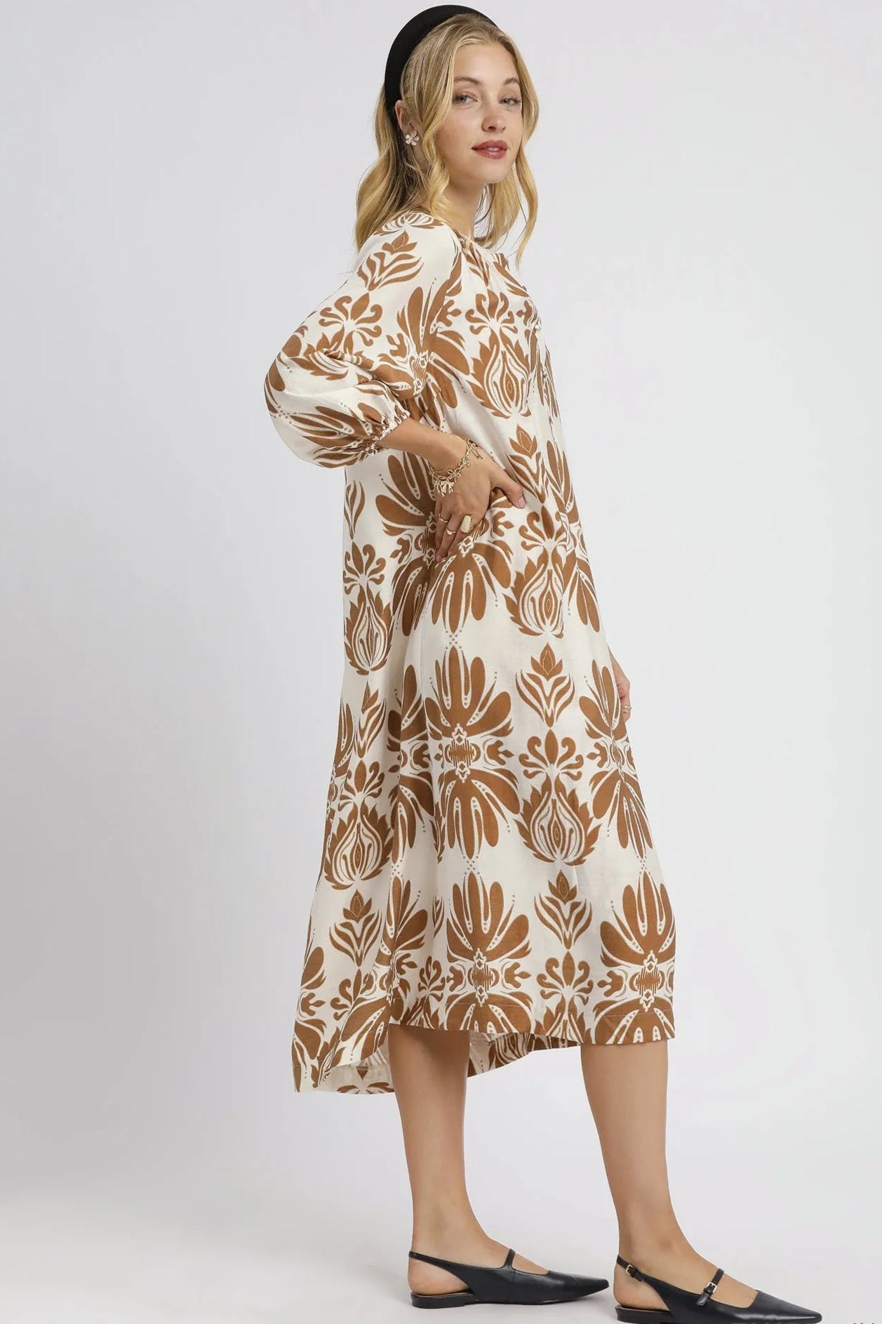 Woman wearing a beige dress with brown floral pattern on a white background