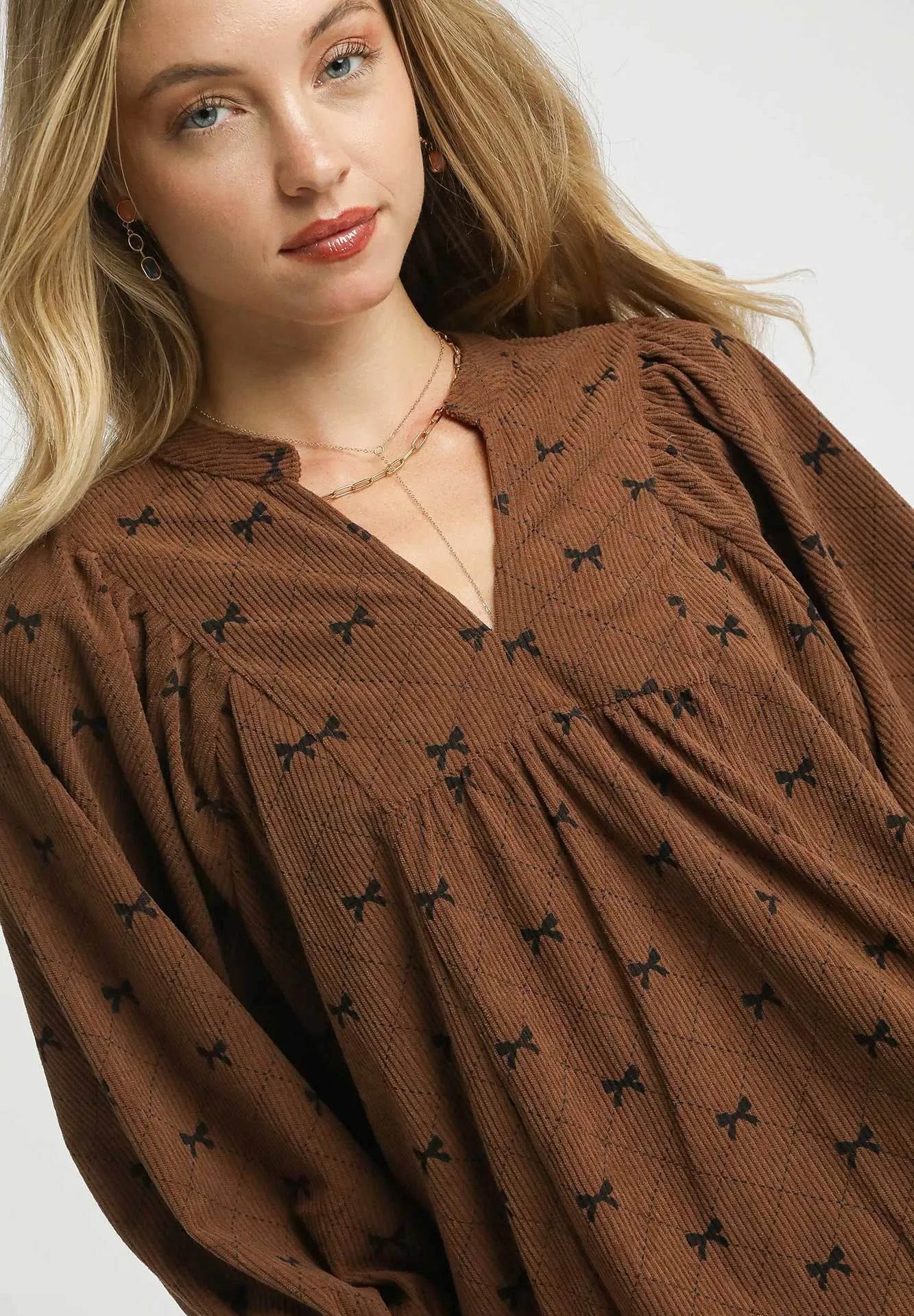 Woman wearing a brown blouse with black patterns on a white background